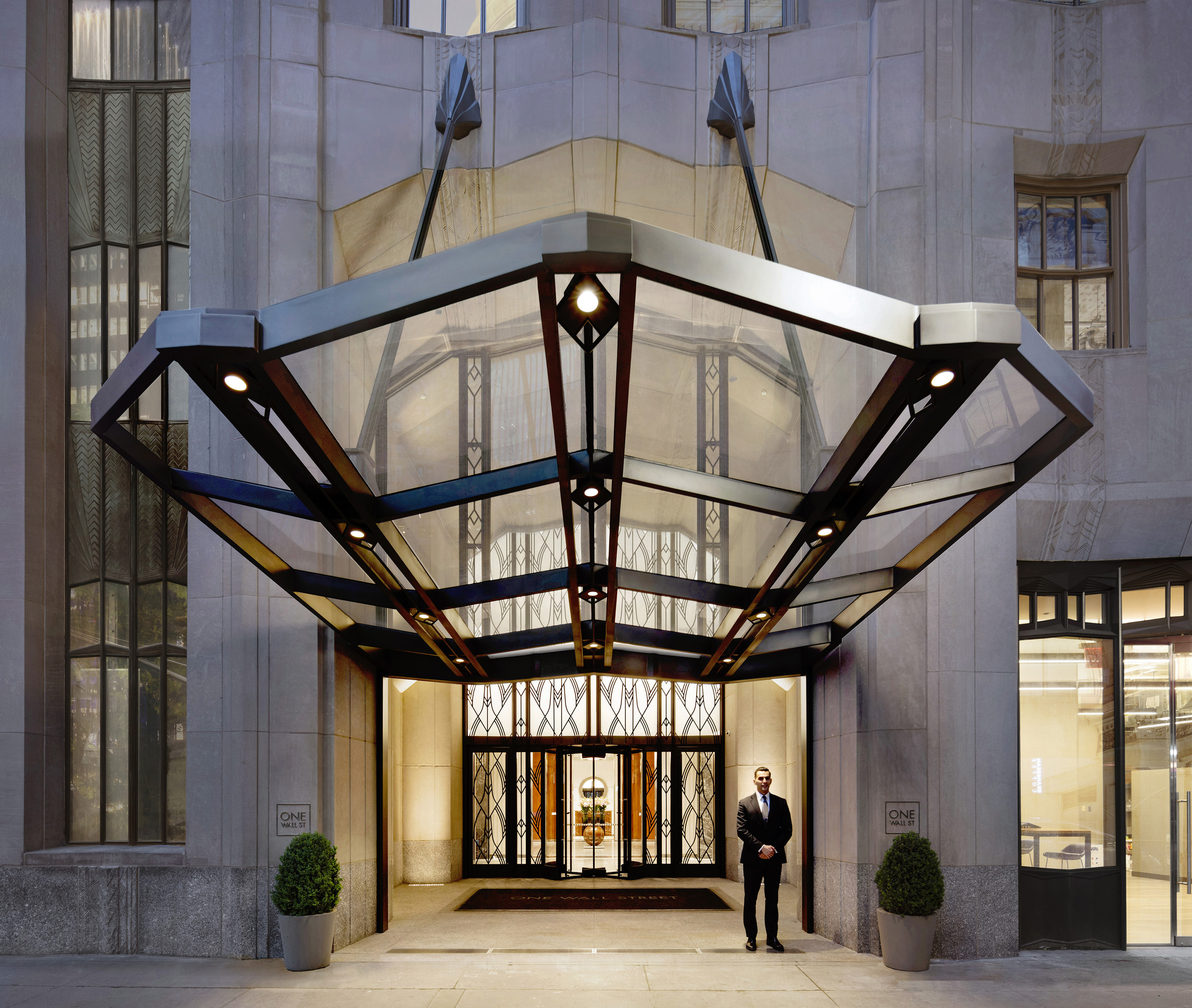 View from across the street of the One Wall Street lobby entrance with a male concierge standing outside the front door.